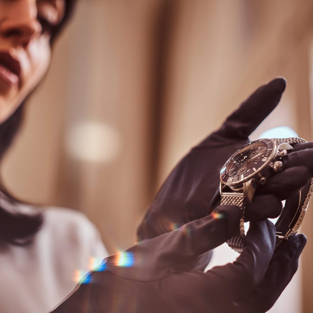 The seller shows an exclusive men's wristwatch from the new collection in the luxury jewelry store